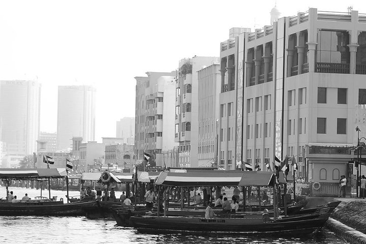 Experience the charm of Dubai as traditional boats glide along the water surrounded by a blend of historical architecture and modern skyscrapers telling the city’s unique story.
